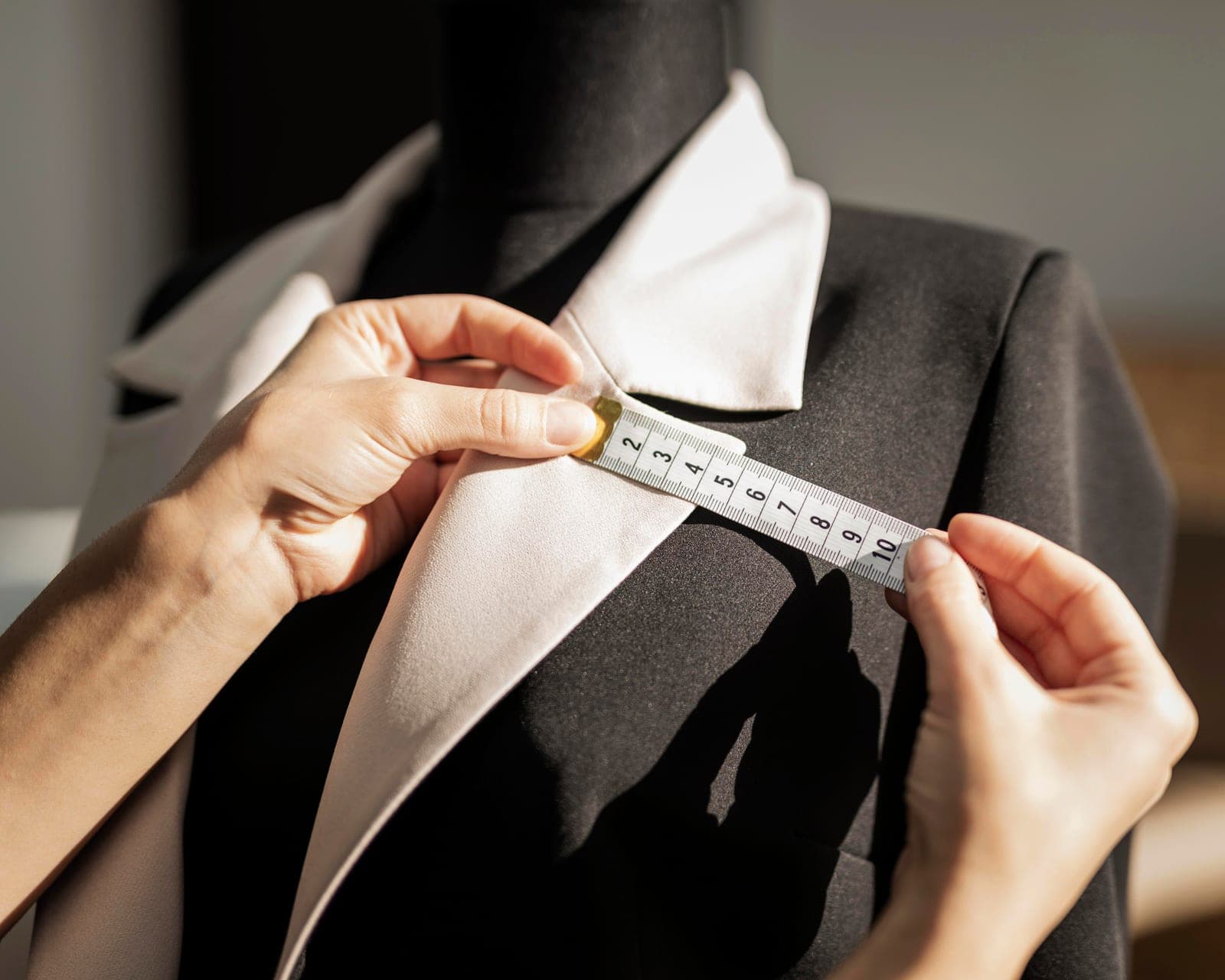 A tailor measuring a jacket collar with a tape measure